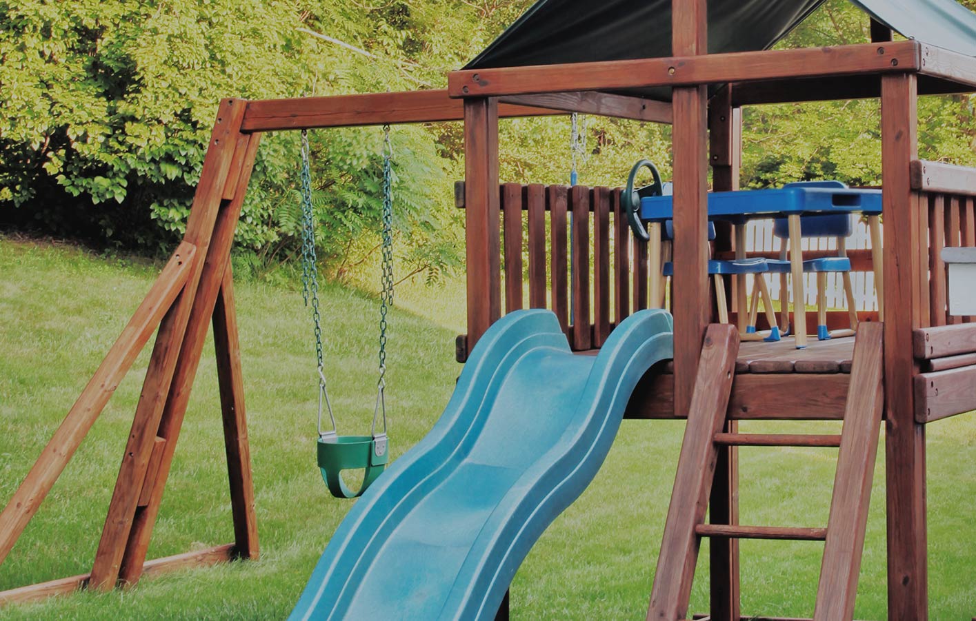 Kinderholzspielplatz mit Rutsche und Schaukeln im grünen Garten.